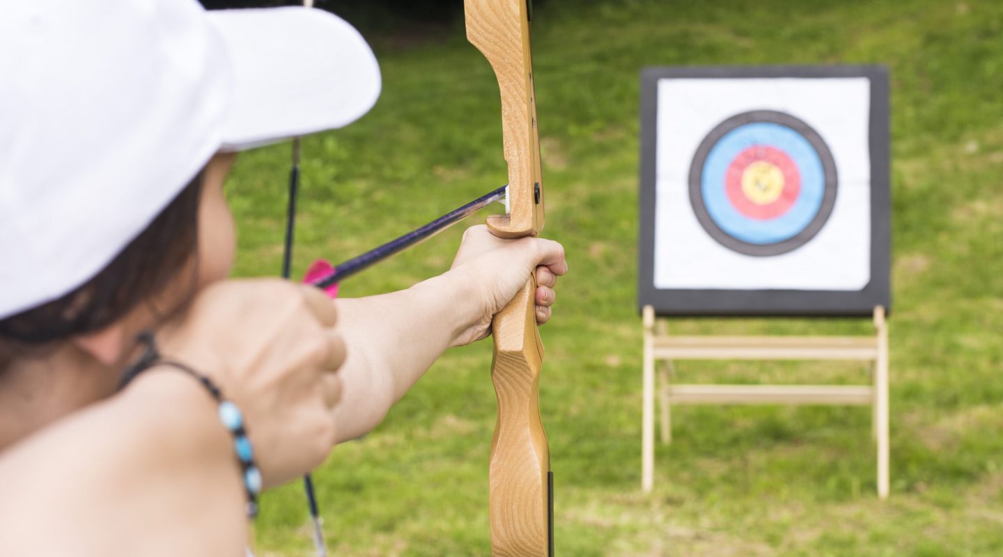 A young female archer holding his bow aiming at a target - sport and recreation concept